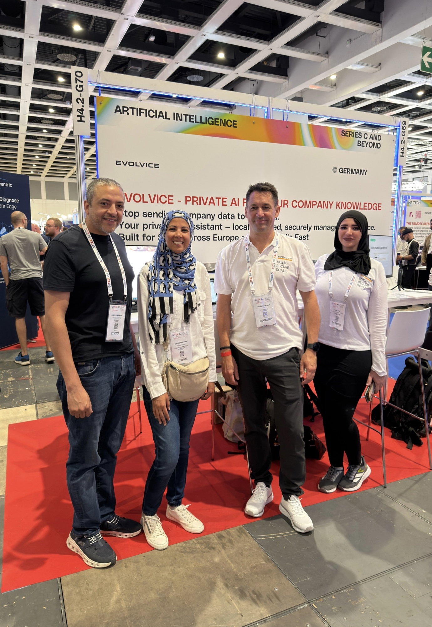 Evolvice team with visitors in front of the Private AI booth backdrop